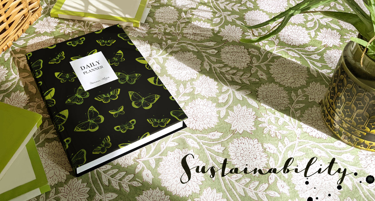 Billy Sustainability banner. Black, hardbound Butterfly Sketch notebook photographed on green patterned fabric.